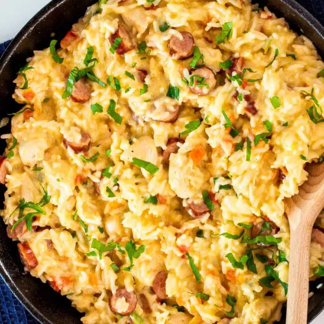 sausage chicken and cheesy rice in a black skillet.