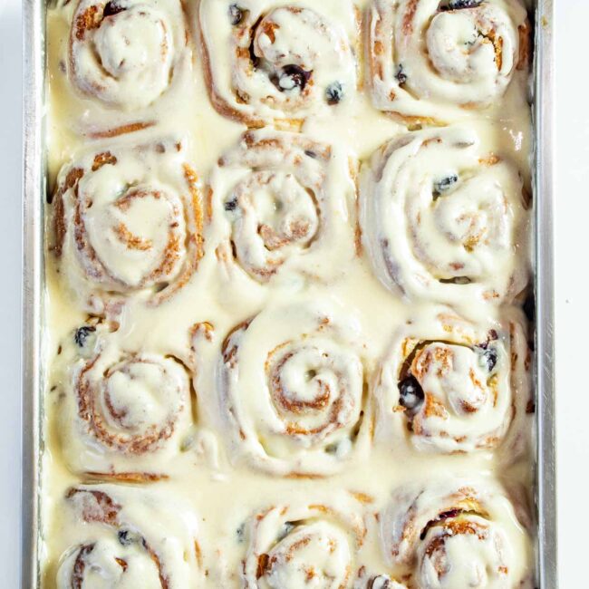 blueberry lemon rolls with cream cheese icing in a baking dish.