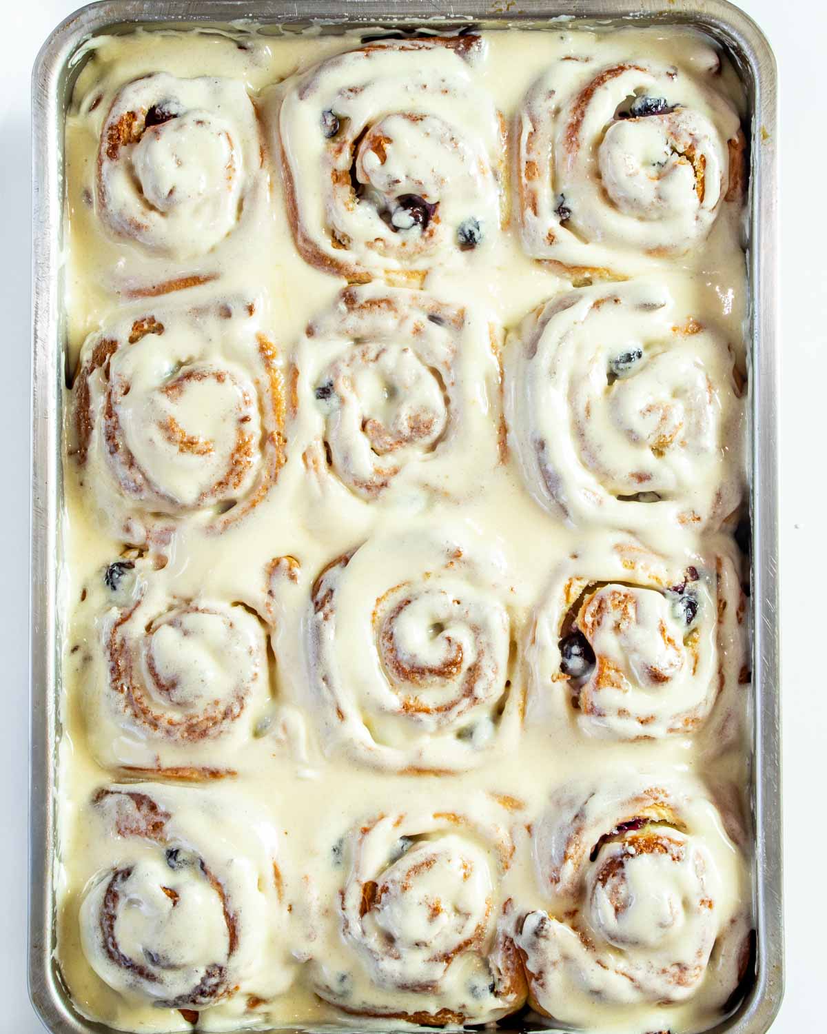 blueberry lemon rolls with cream cheese icing in a baking dish.