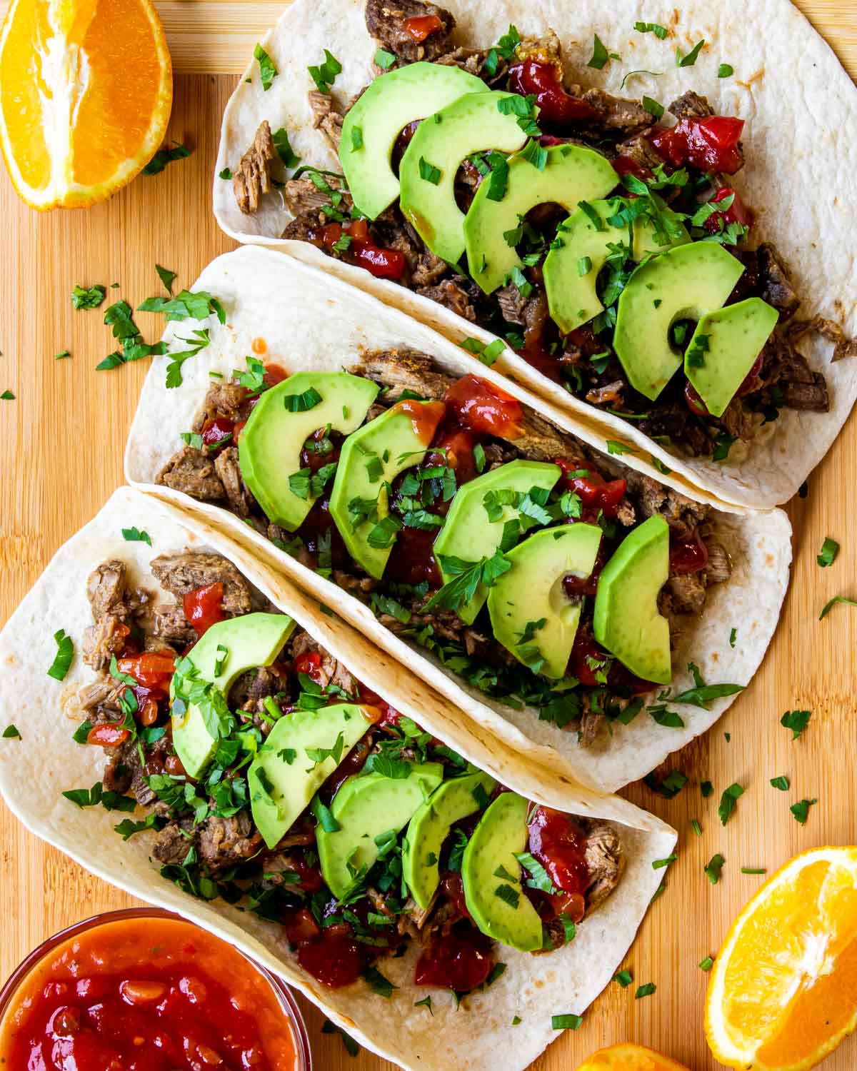 3 beef carnitas tacos on a cutting board.