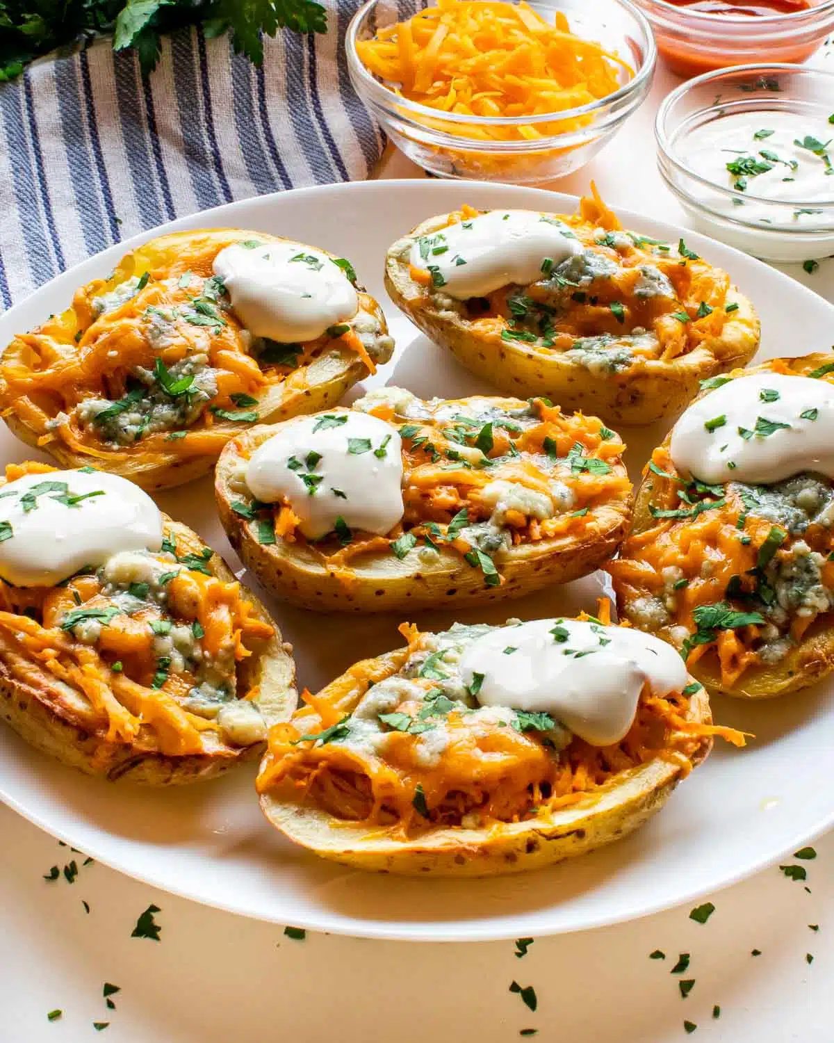 a white plate loaded with buffalo chicken potato skins.