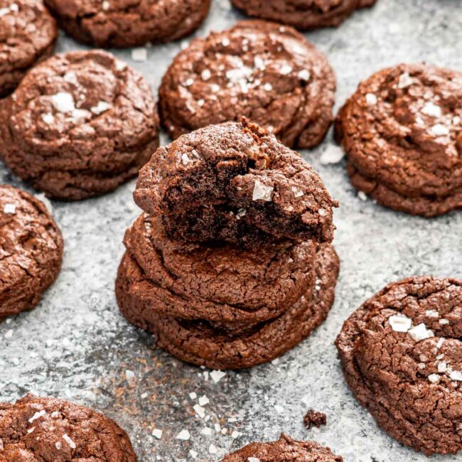 a stack of chocolate brownie cookies with the top one broken in half.