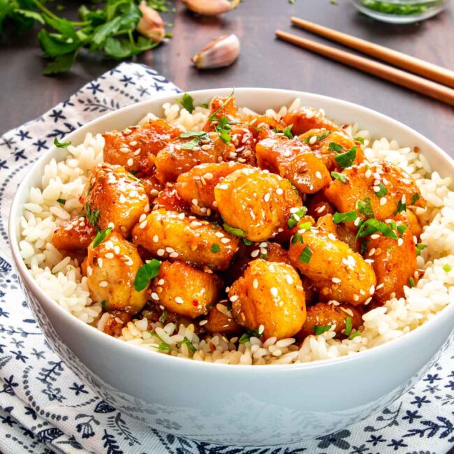 honey garlic chicken bites on a bed of rice in a bowl.