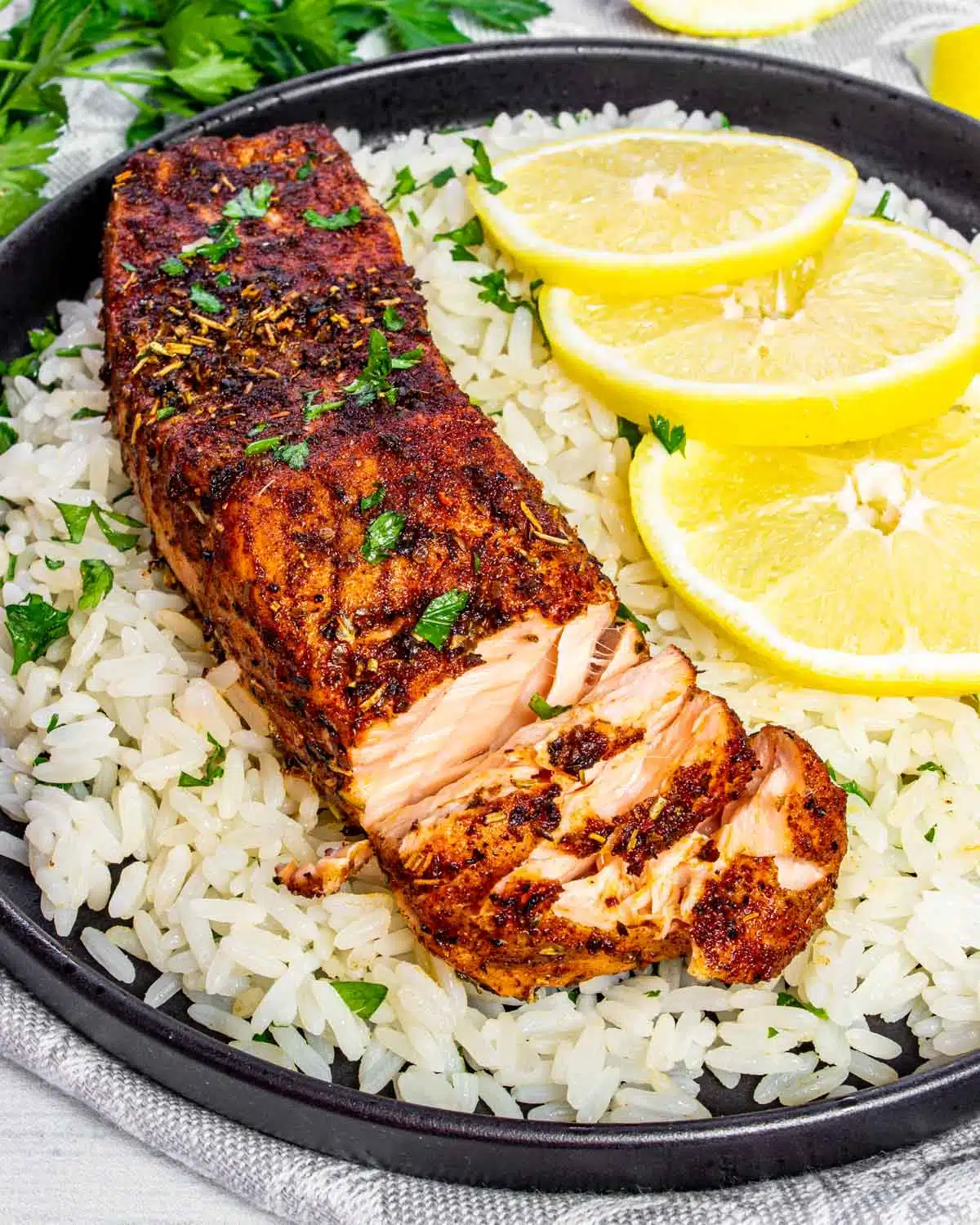 a salmon fillet on a bed of rice with lemon slices.