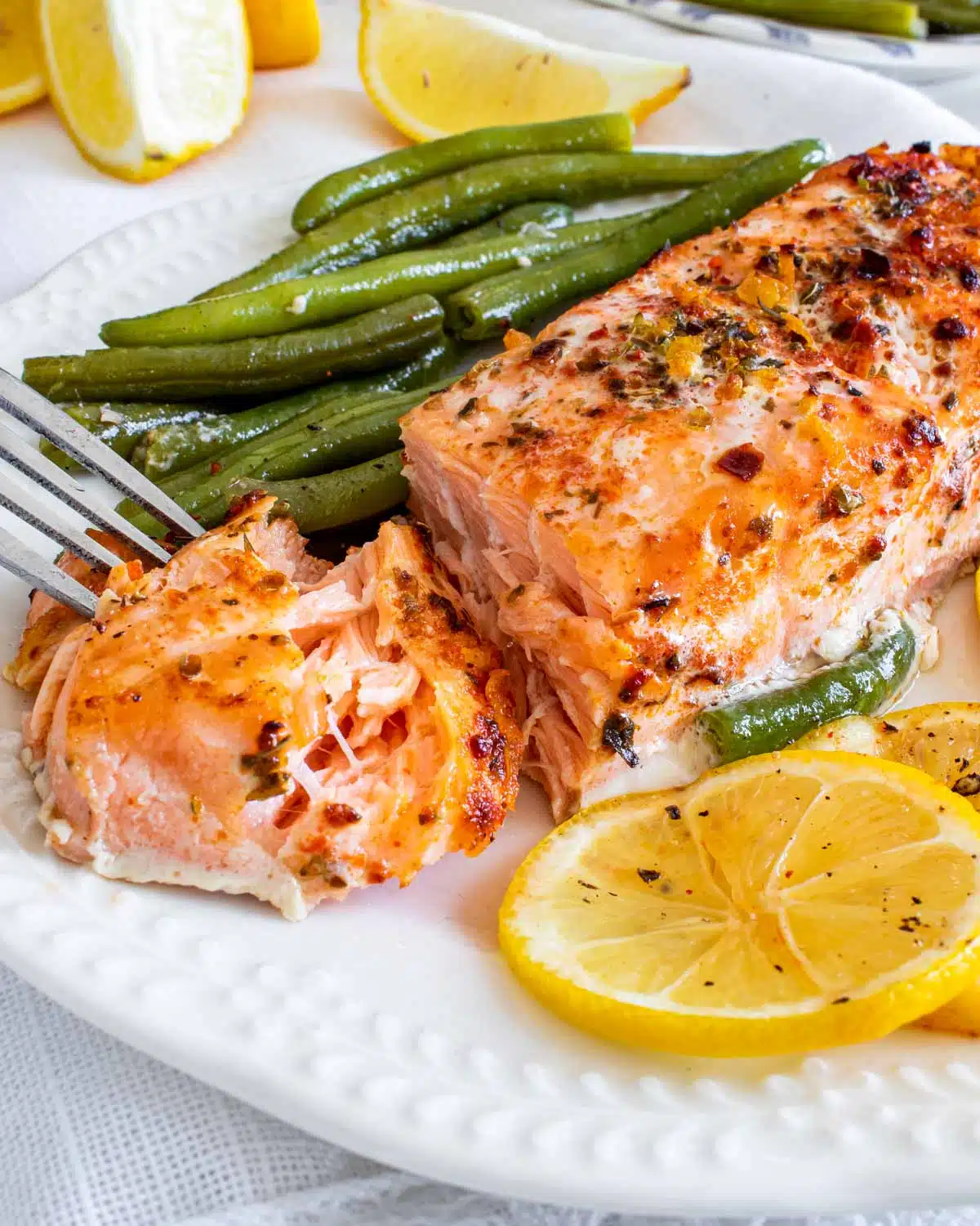 salmon and green beans with a lemon slice on a plate.