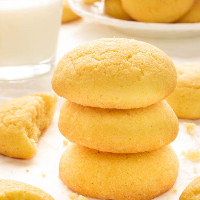 a stack of amish sugar cookies next to a glass of milk.