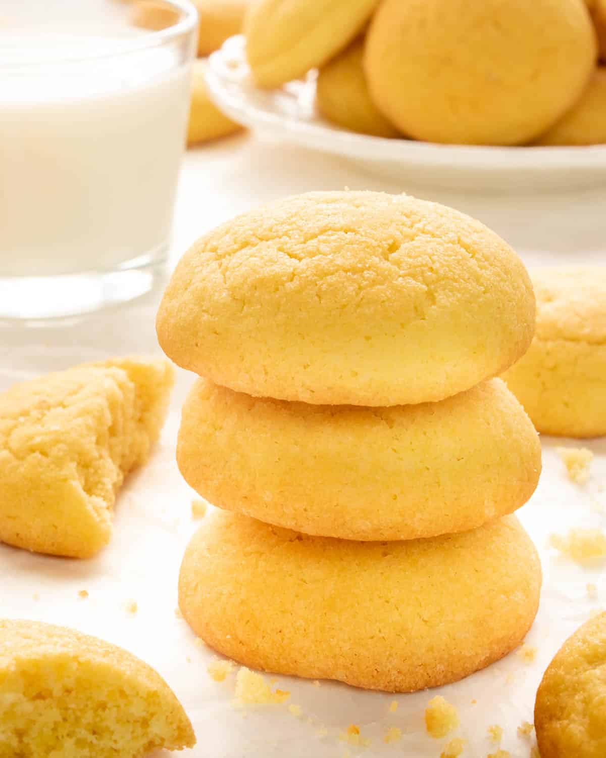 a stack of amish sugar cookies next to a glass of milk.