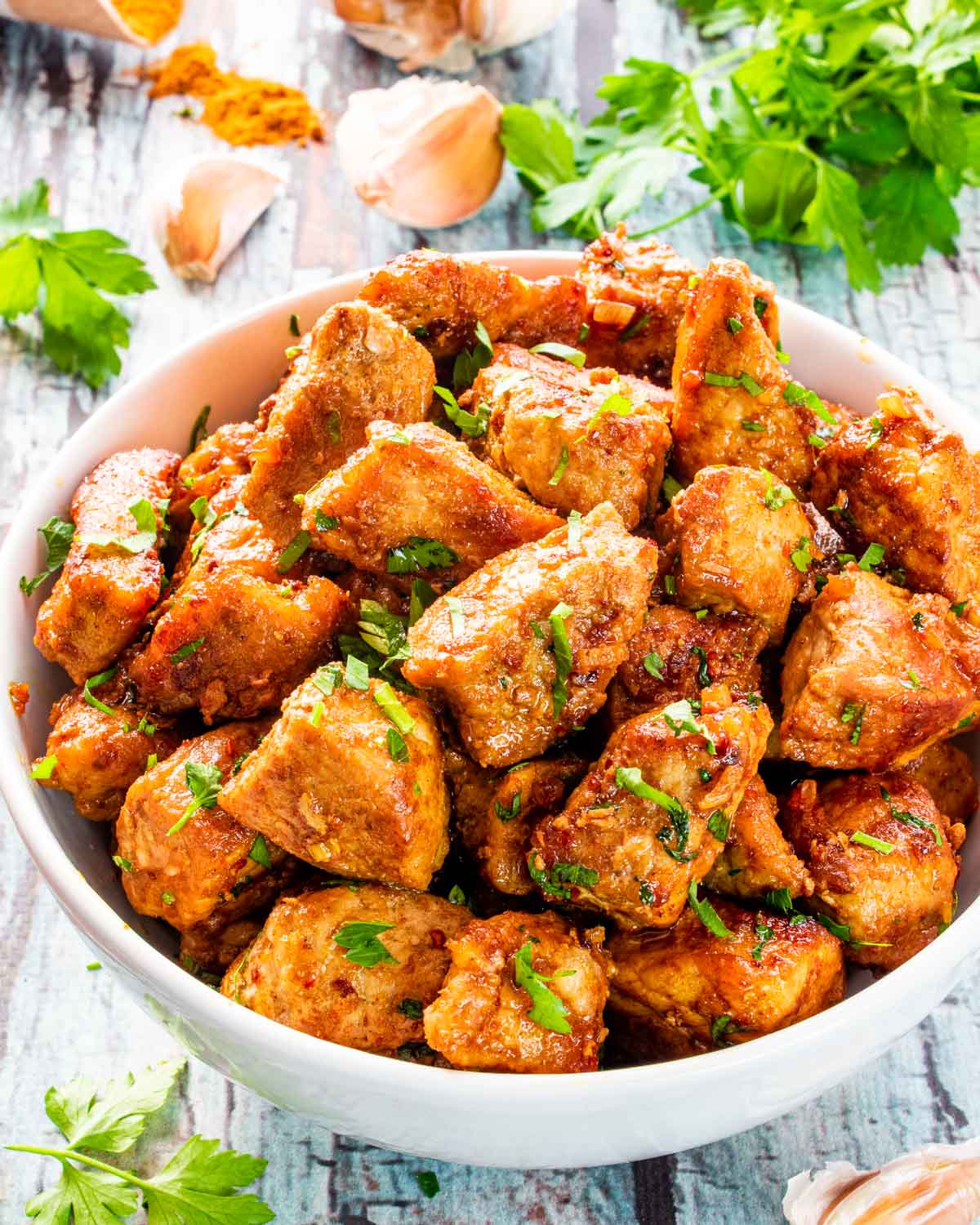 cajun pork bites garnished with parsley in a bowl.