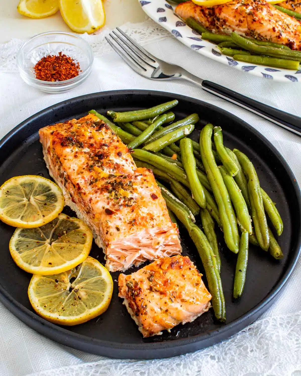 salmon and green beans with a lemon slice on a plate.