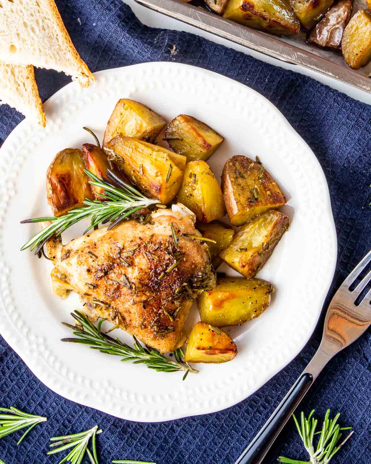 rosemary chicken and potatoes on a white plate.