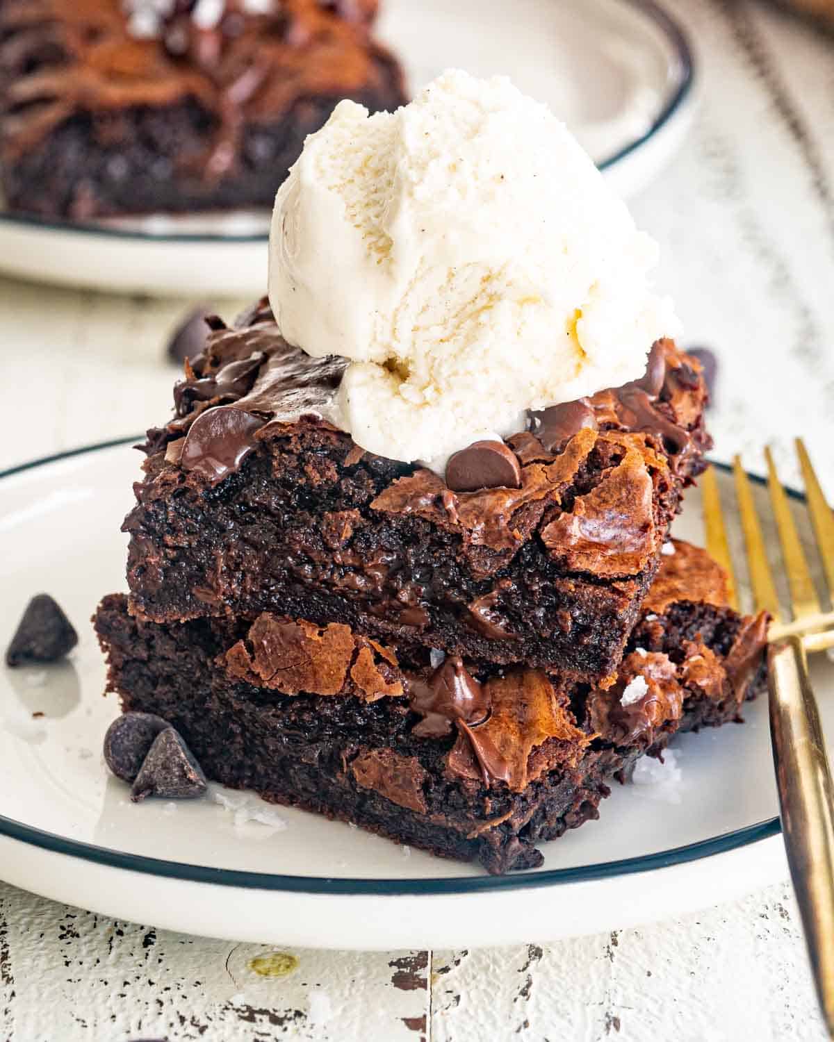 two brownies stacked with a scoop of ice cream on a white plate.