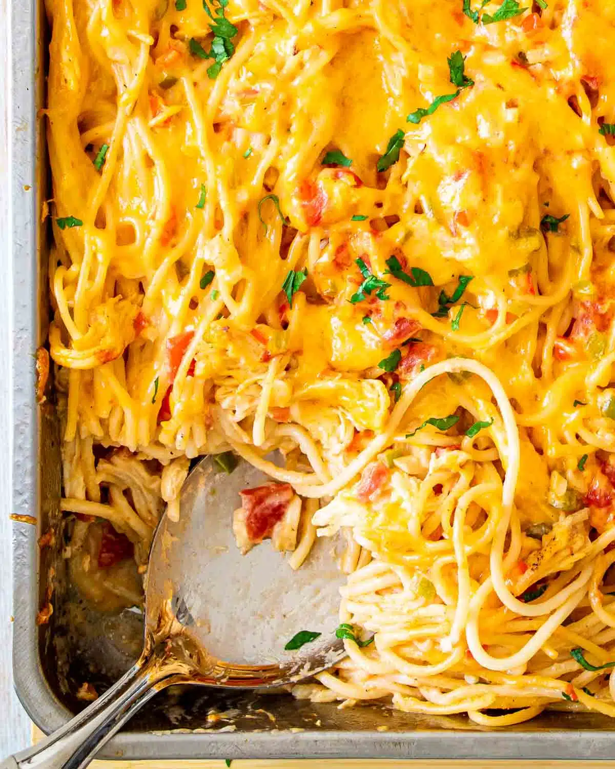 chicken spaghetti in a casserole dish with a serving spoon inside.