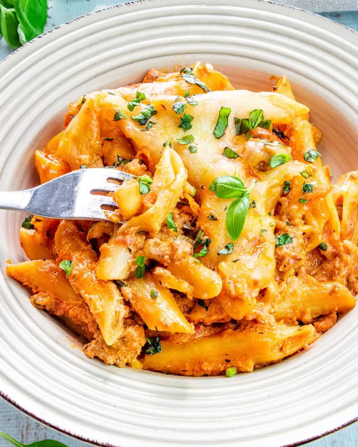sausage pasta made in one pot in a plate garnished with basil.