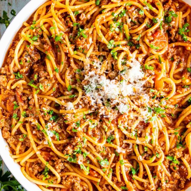 spaghetti made in one pot garnished with parmesan in a white bowl.
