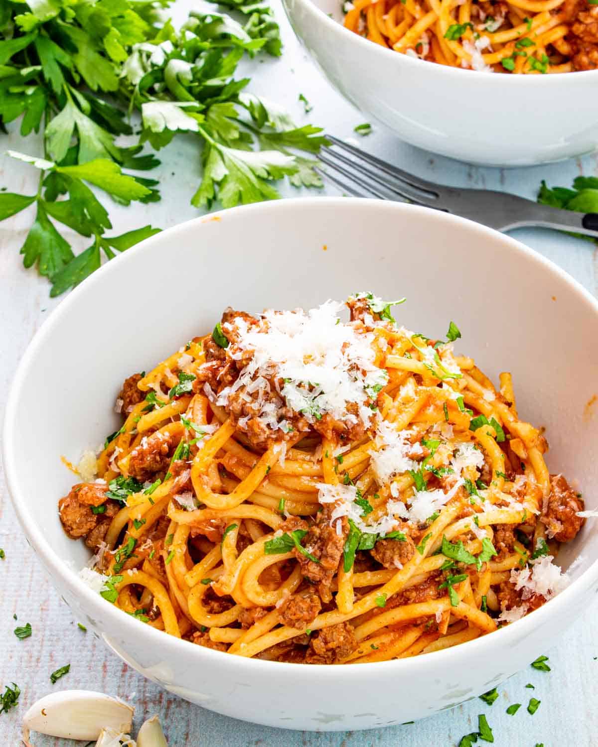 meat spaghetti on a white plate garnished with parsley.