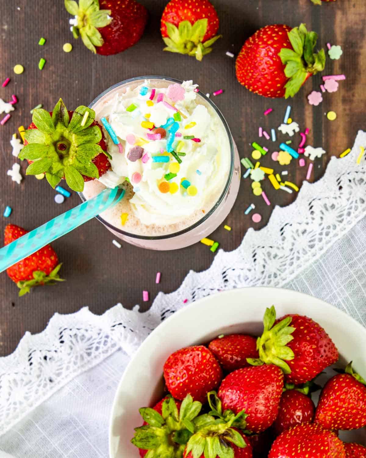 strawberry milkshake topped with whipped cream and sprinkles.