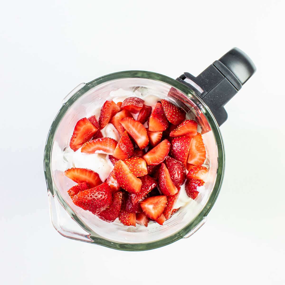 ingredients in a blender ready to make a strawberry milkshake.