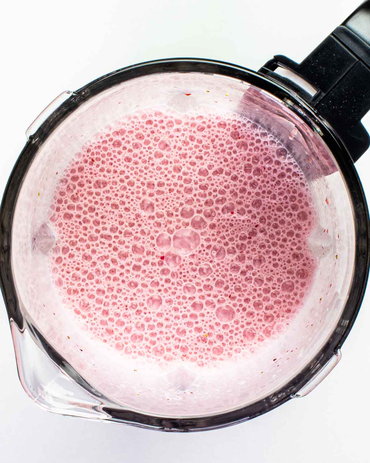 freshly blended strawberry milkshake in a blender.