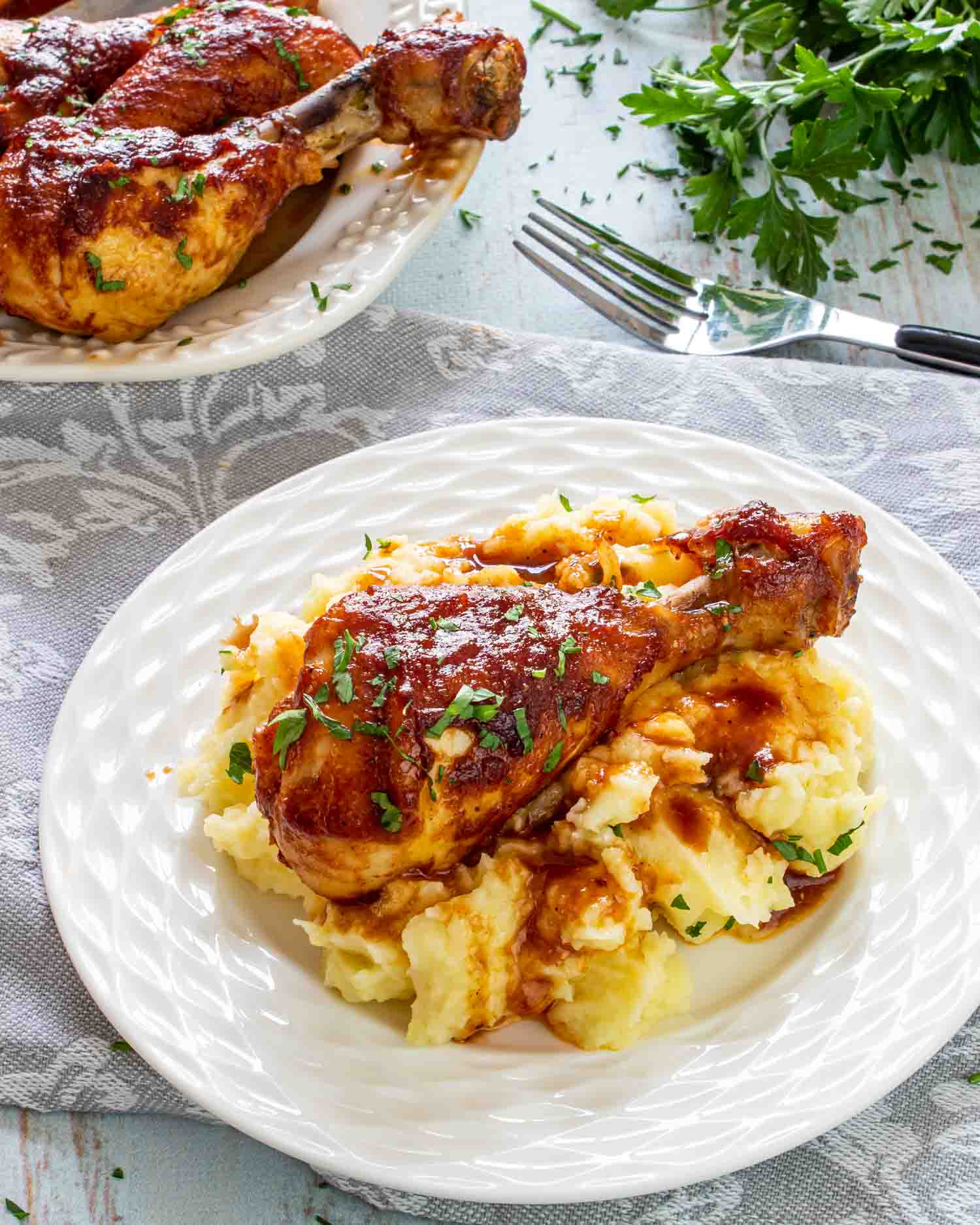 a bbq chicken drumsticks on a bed of mashed potatoes.