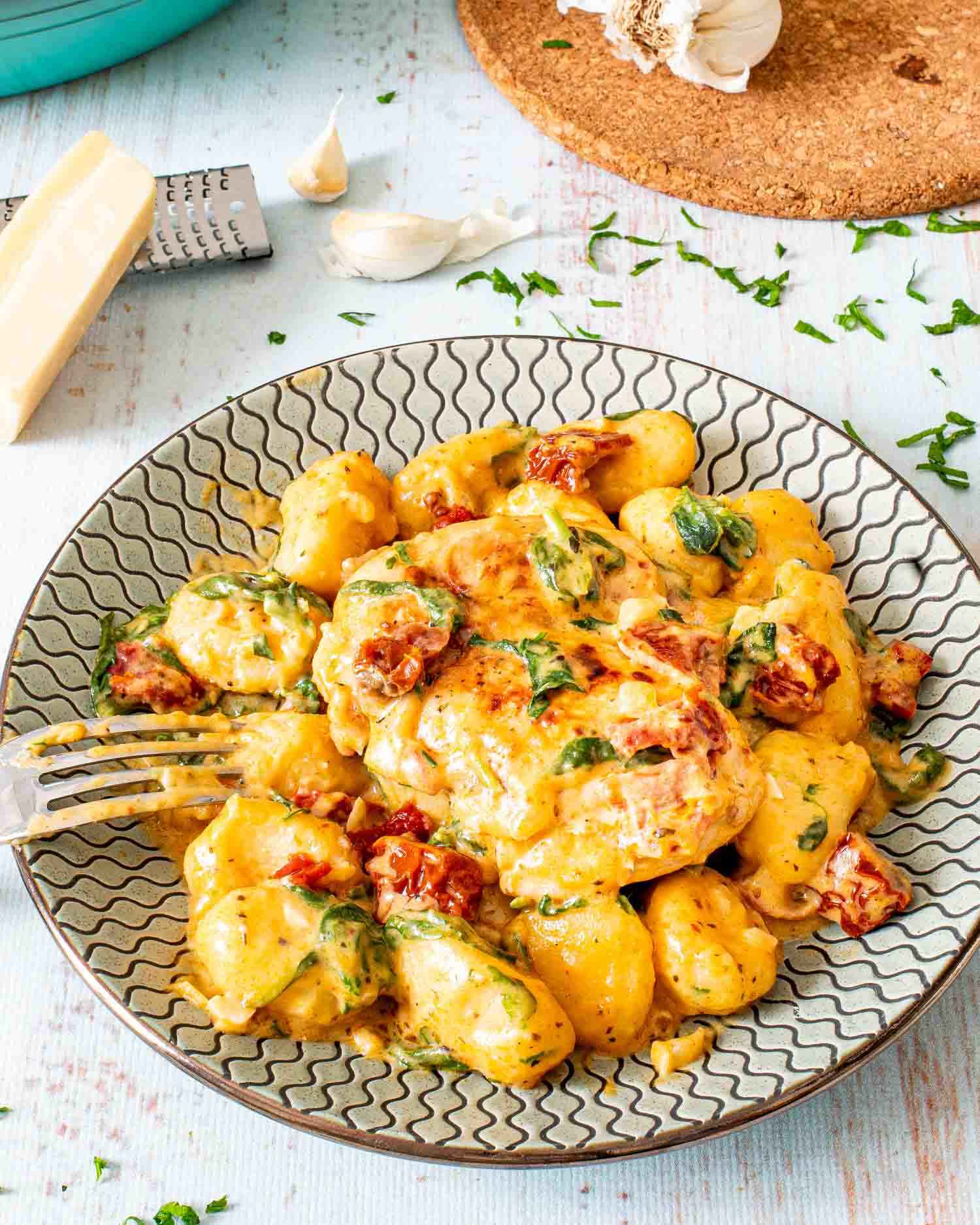 creamy chicken gnocchi on a plate with a fork in it.