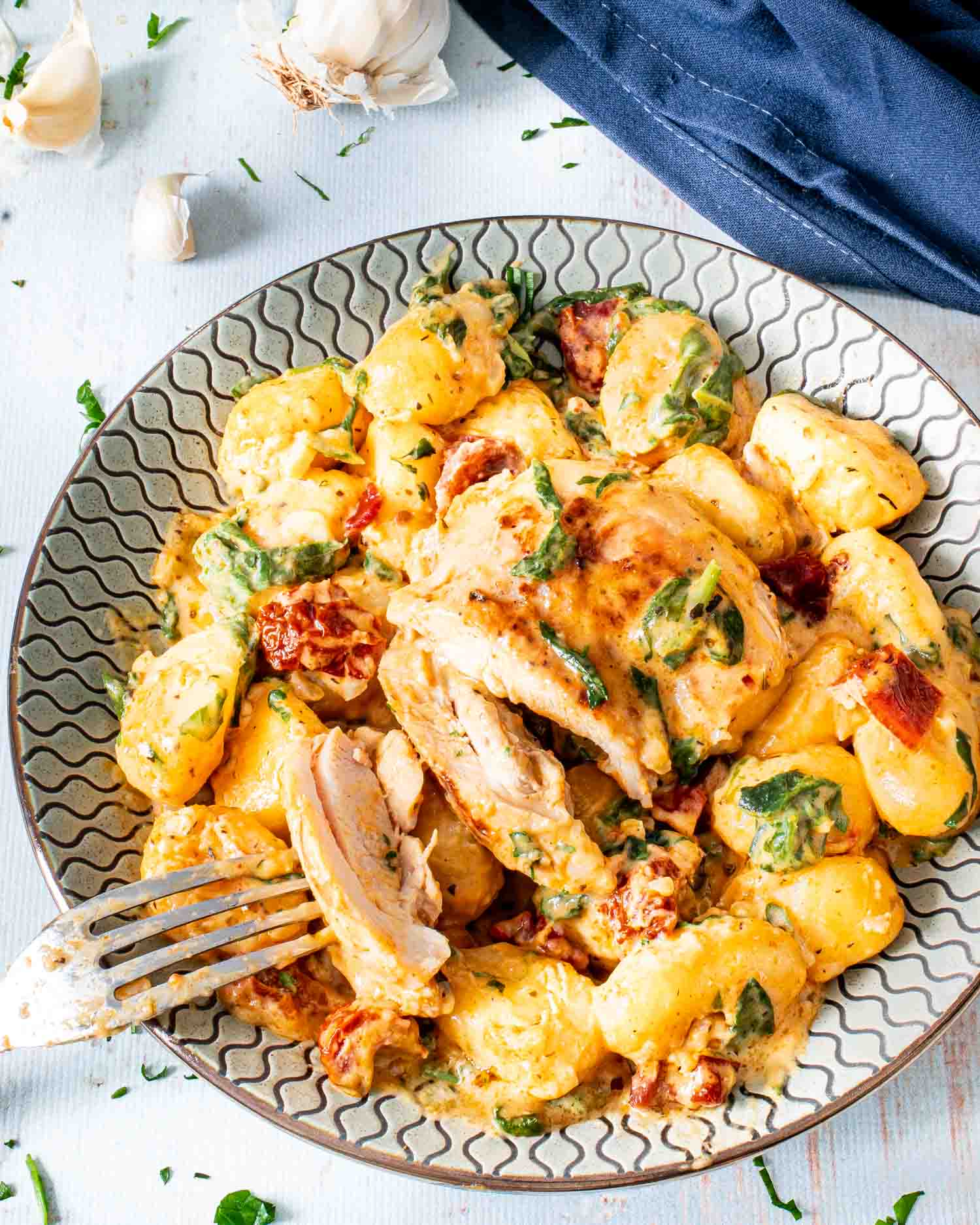 creamy chicken gnocchi on a plate with a fork in it.