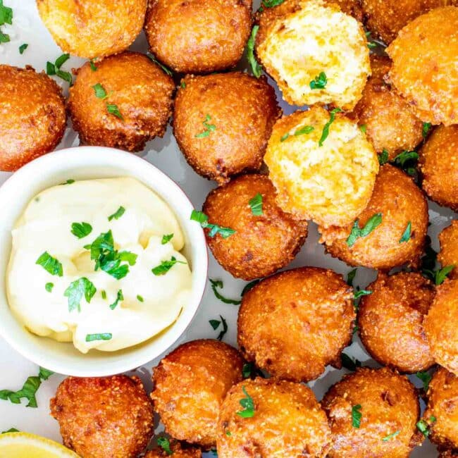 hush puppies on a plate with dipping sauce.