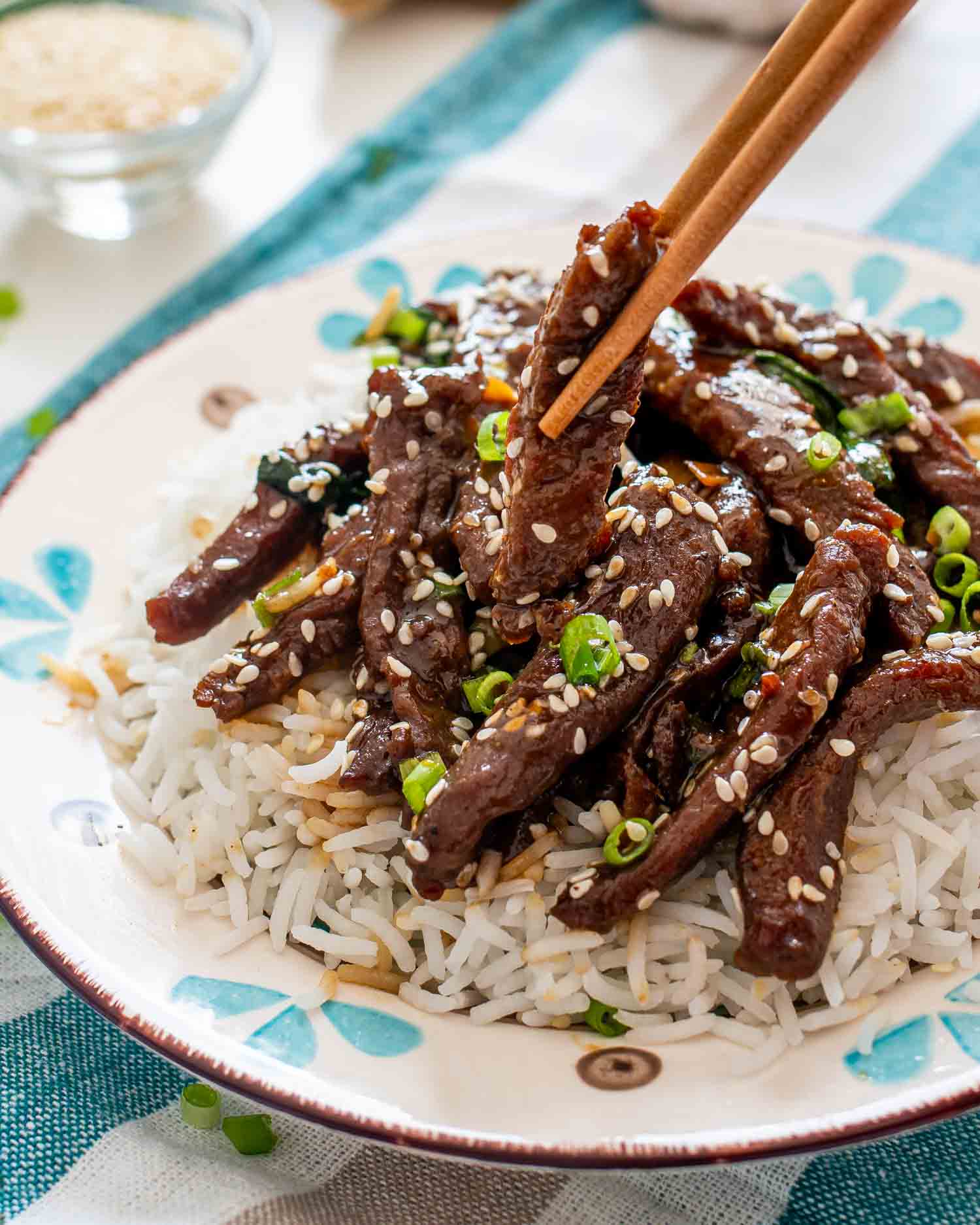 chinese sizzling beef on a bed of rice in a plate.