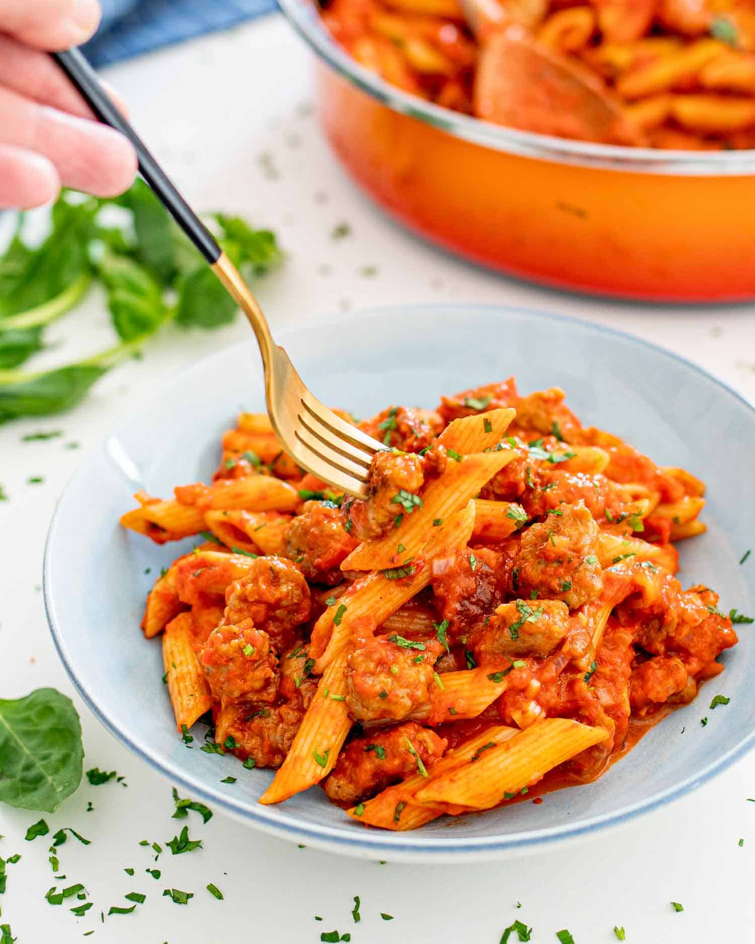 a serving of creamy red pepper sausage pasta in a blue bowl.