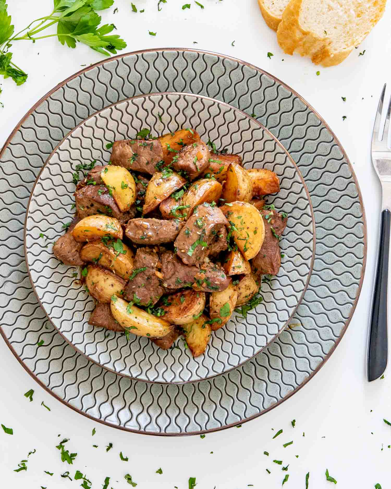 garlic butter steak and potatoes serving on a plate garnished with parsley.