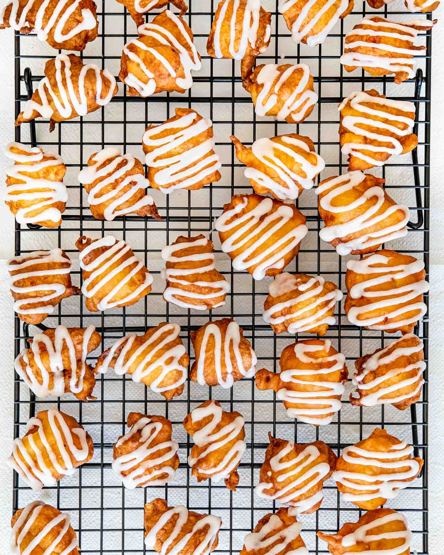 glazed peach fritters on a cooling rack.