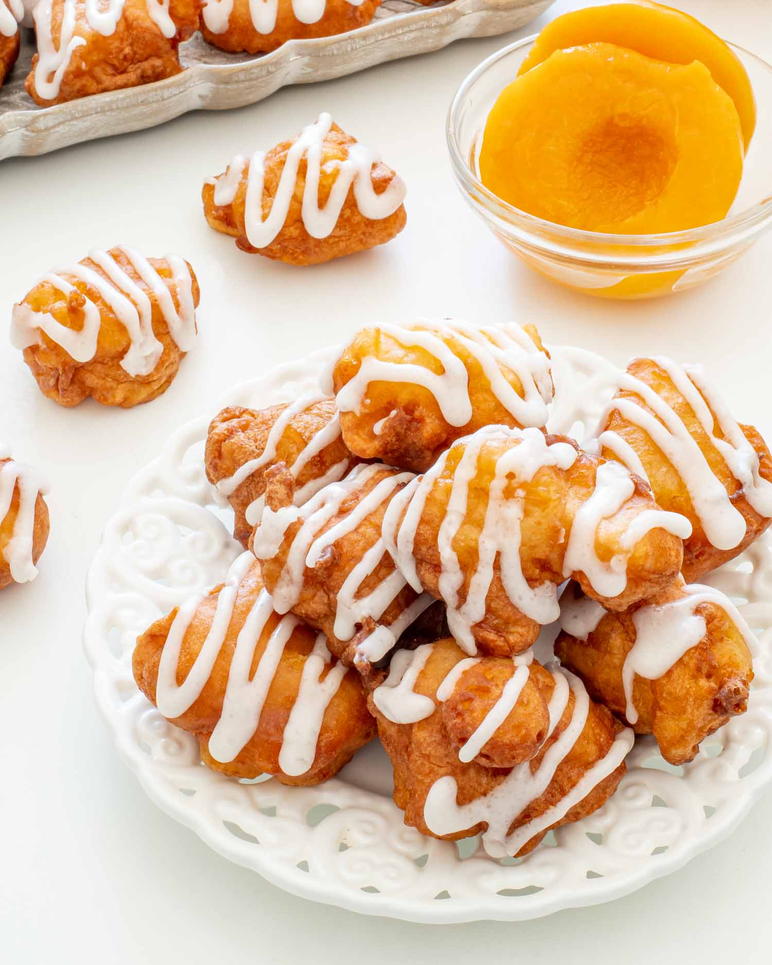 a few glazed peach fritters on a white plate.