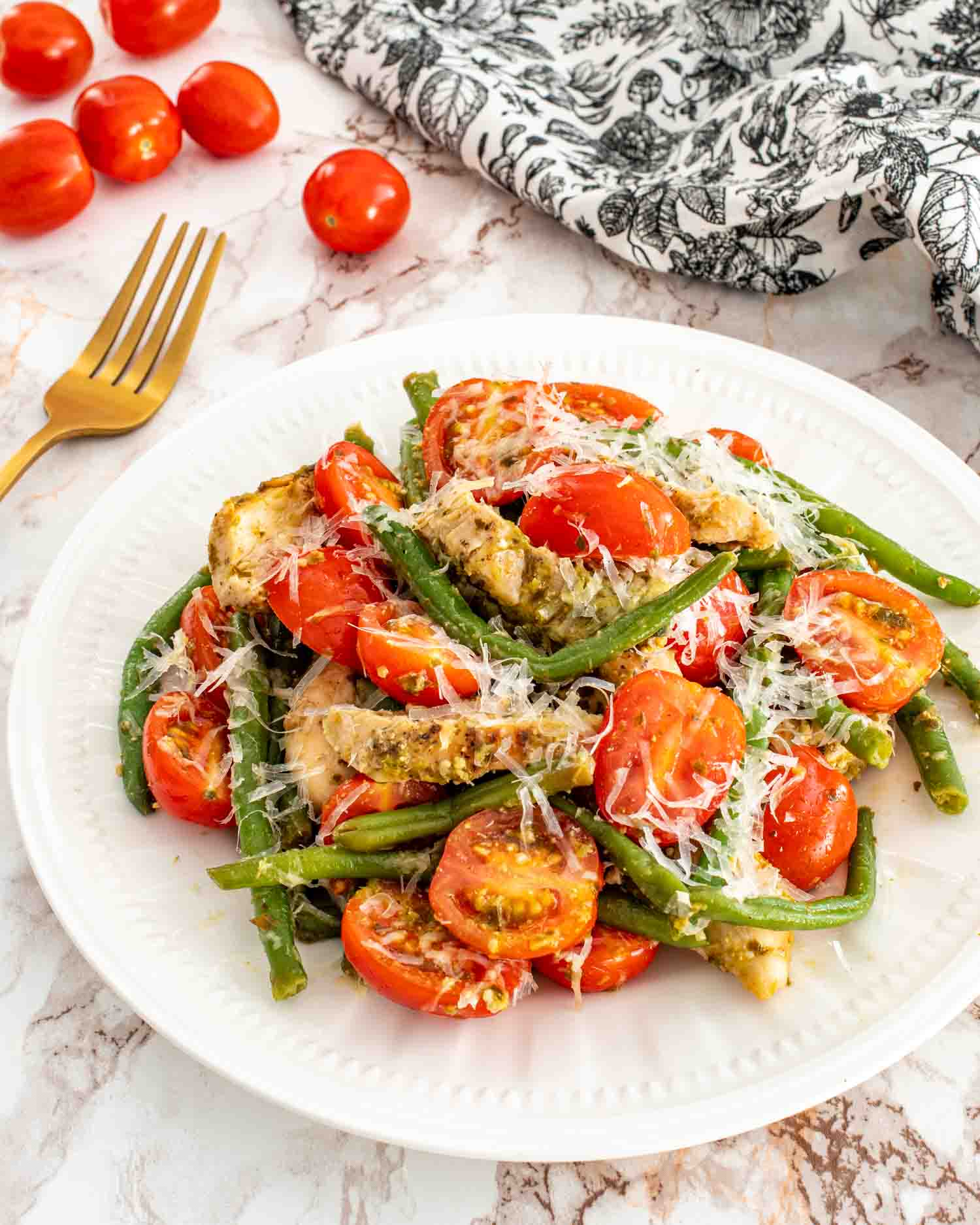 a serving of pesto chicken and veggies on a white plate.