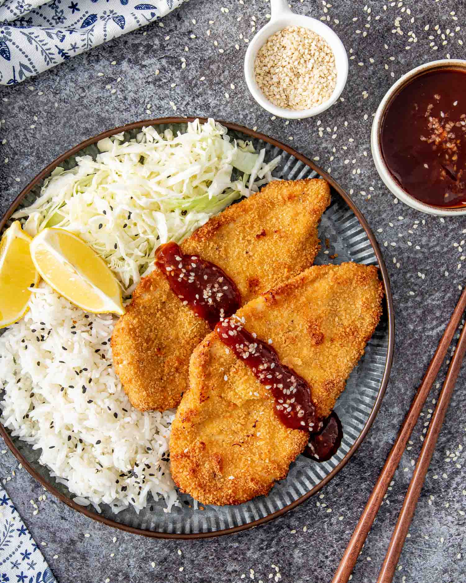 2 pieces of chicken katsu with tonkatsu sauce with rice and 2 lime wedges.