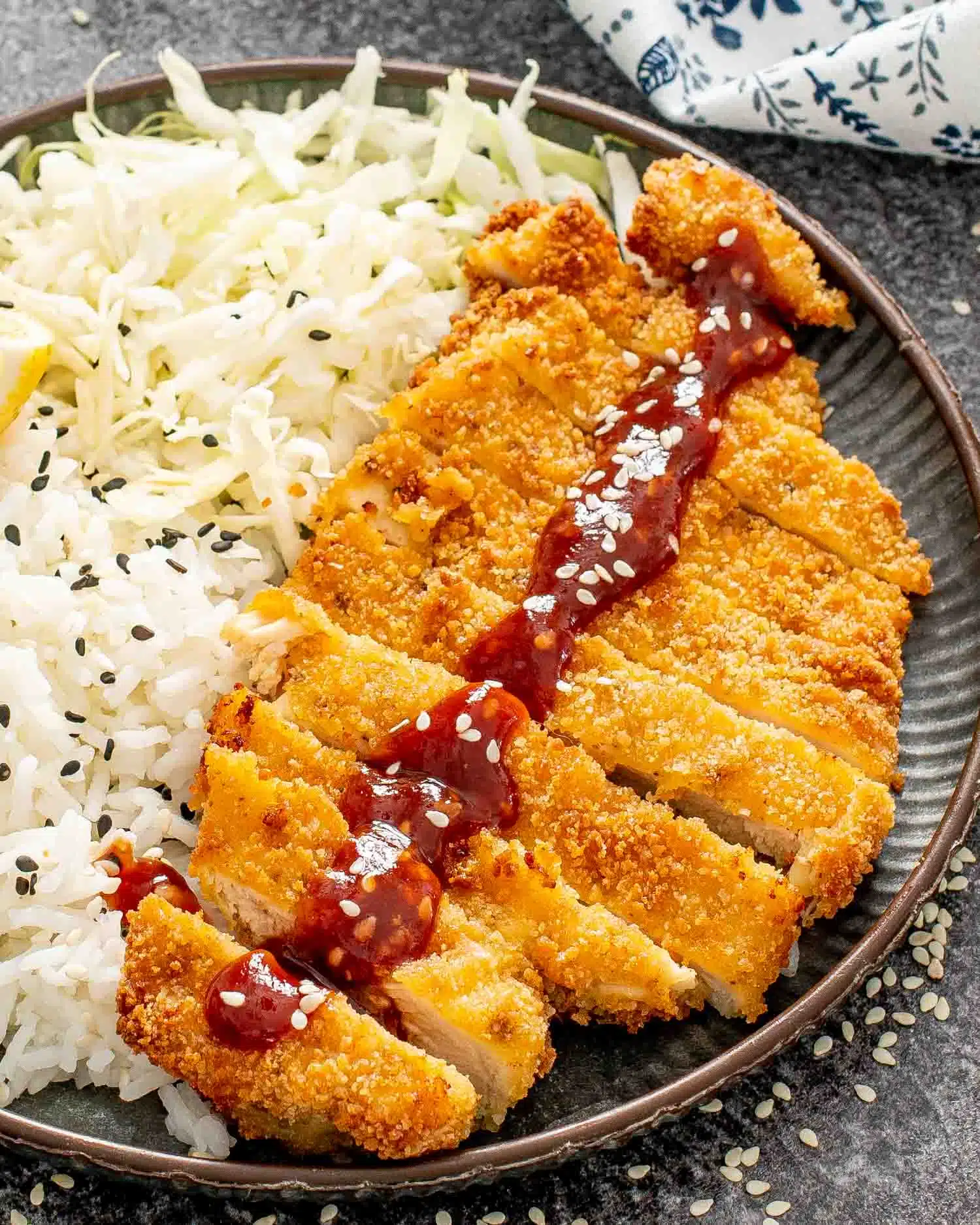 sliced up chicken katsu on a plate with rice and tonkatsu sauce.