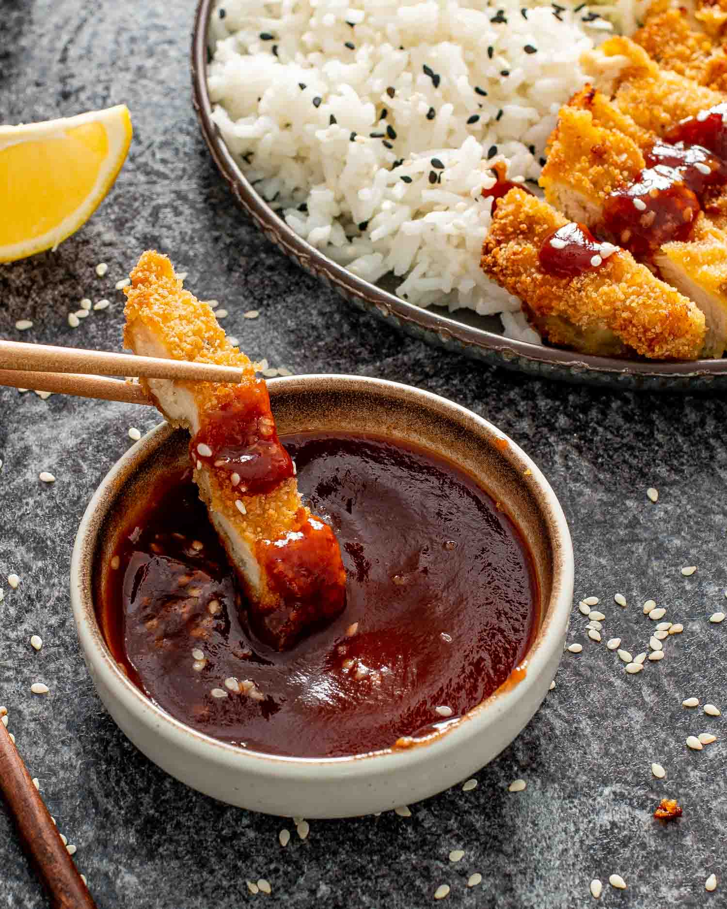a piece of chicken katsu in dipped in a bowl with tonkatsu sauce.