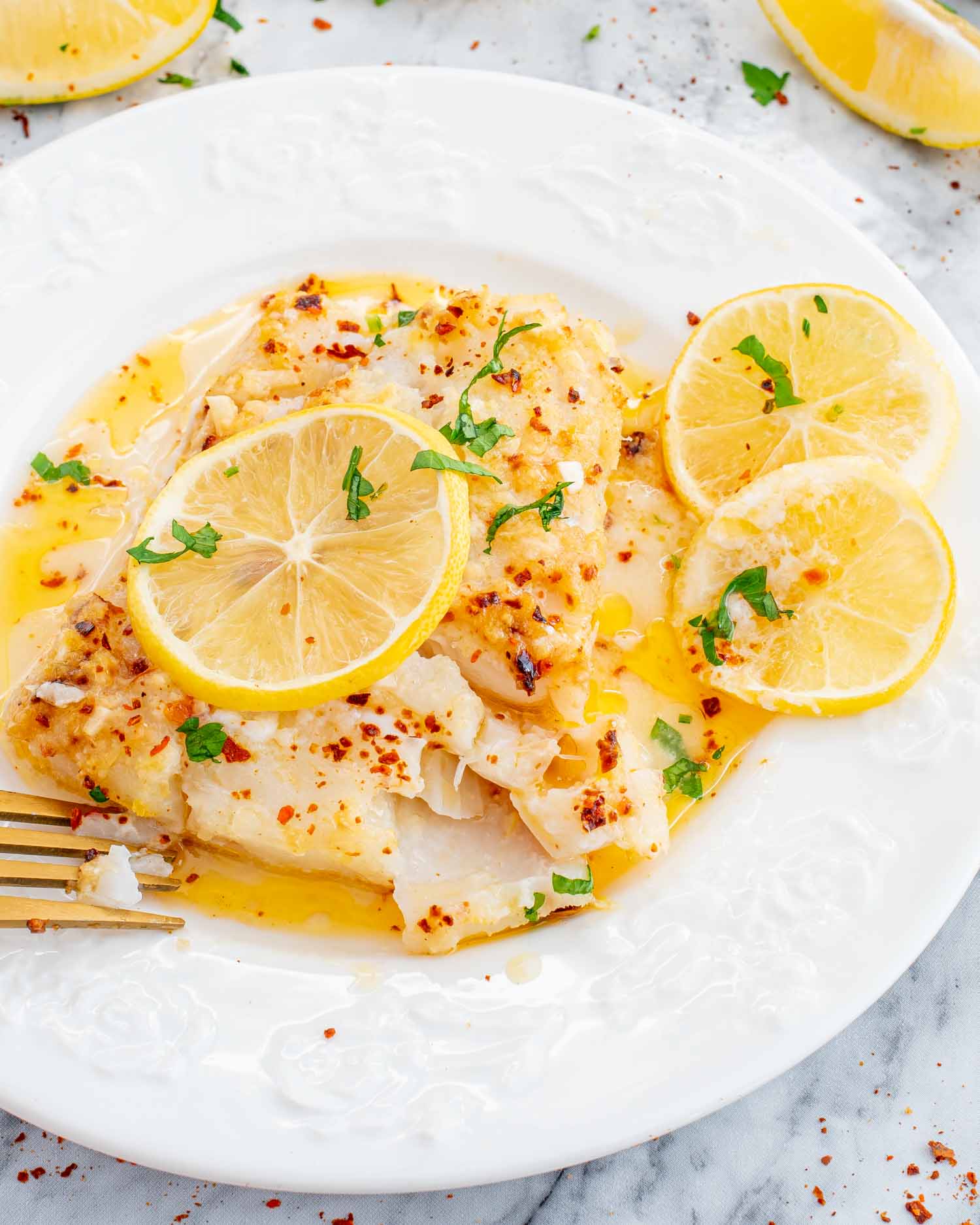 a serving of baked lemon butter cod on a white plate.
