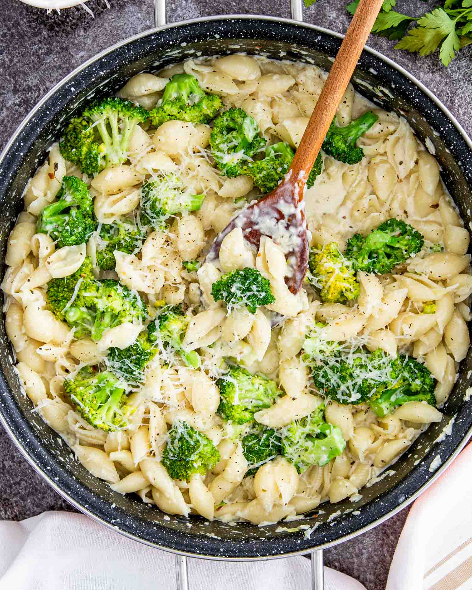creamy broccoli pasta in a skillet with a wooden spoon inside.