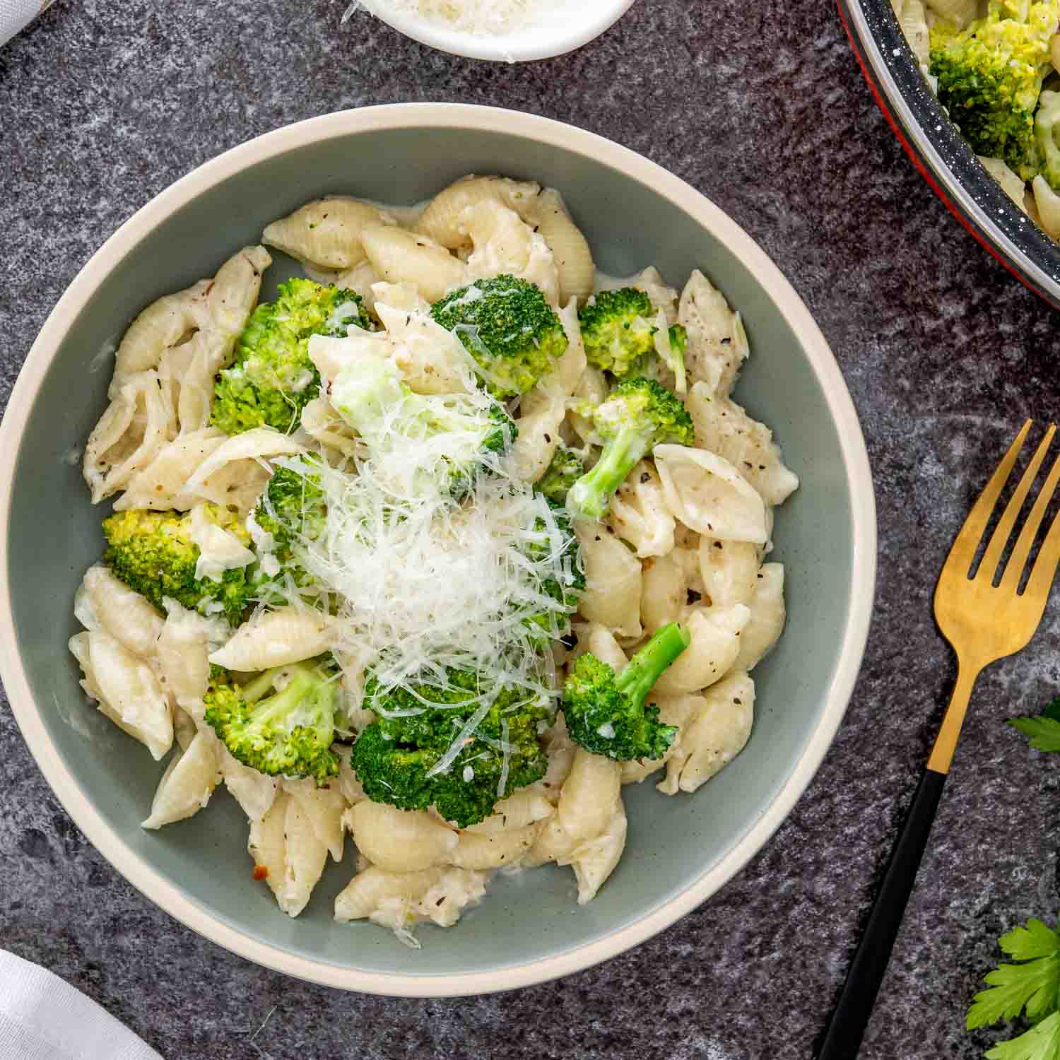 a serving of creamy broccoli pasta in a bowl garnished with parmesan cheese.