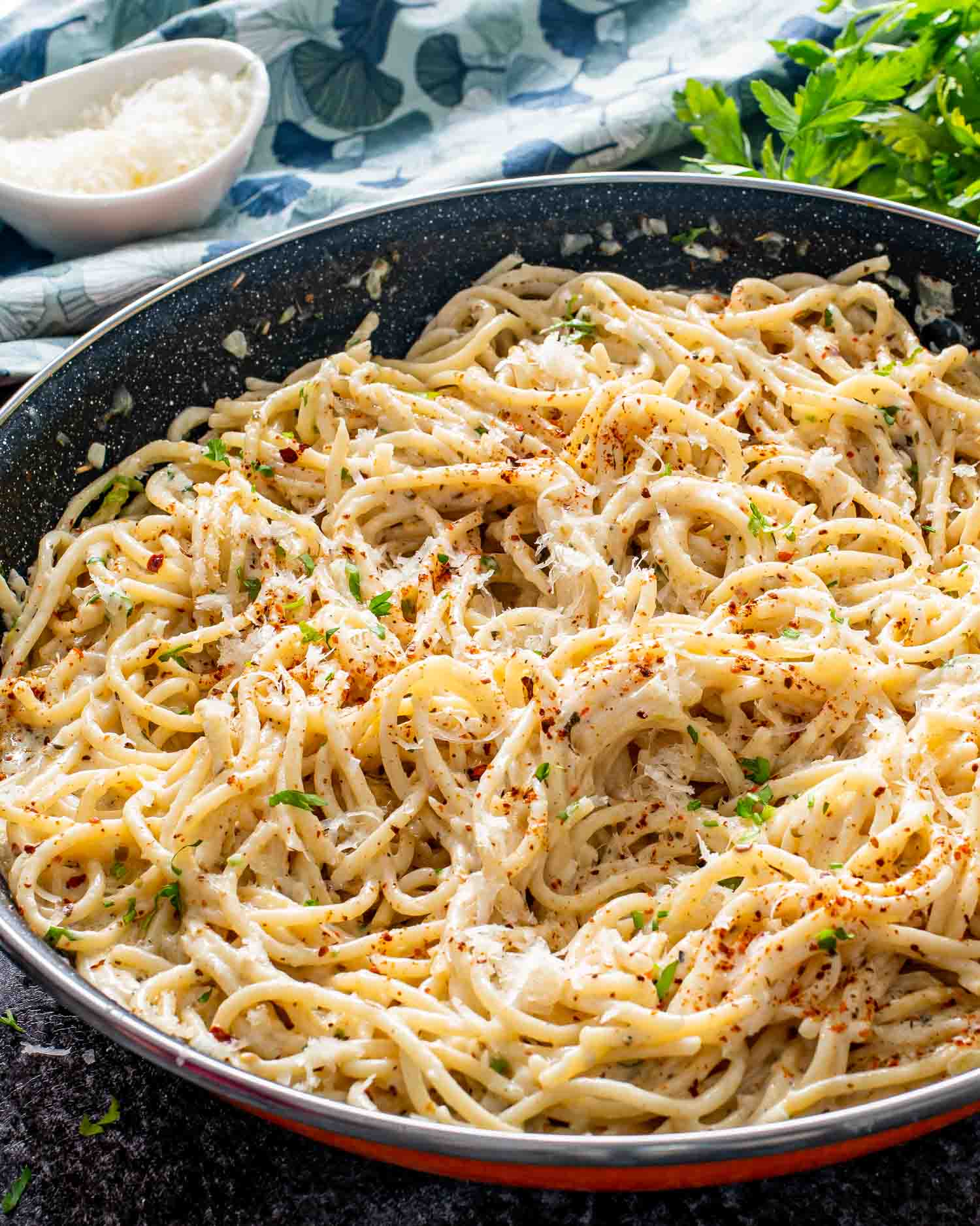 creamy garlic butter spaghetti in a black skillet garnished with parmesan cheese.