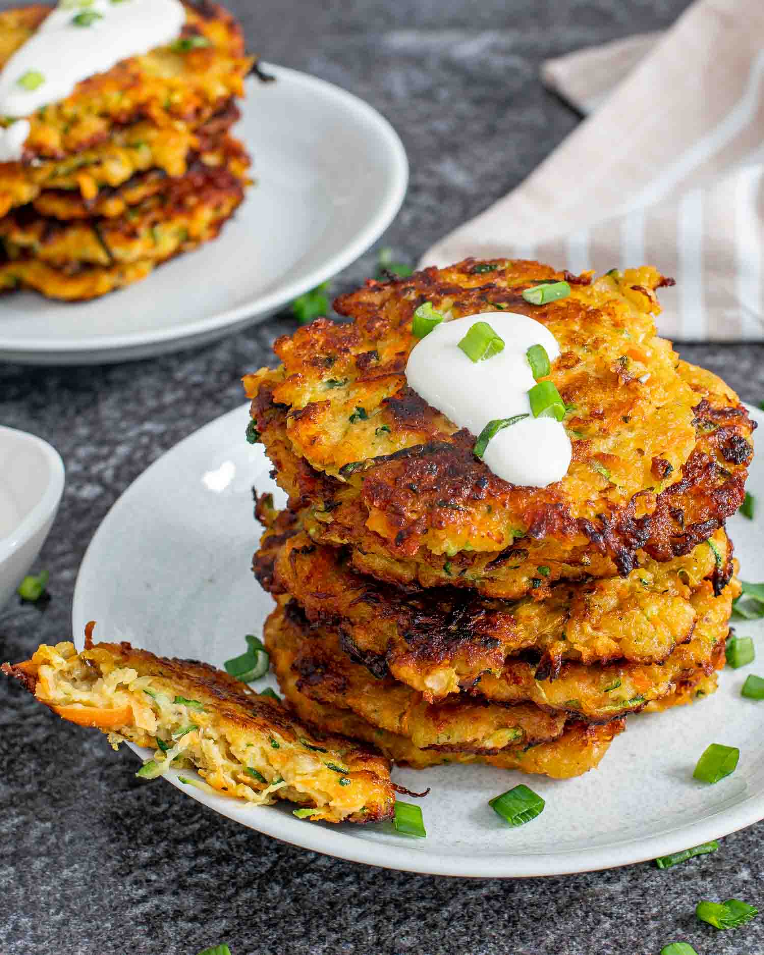 vegetable fritters on a plate garnished with parsley and a dollop of sour cream.f