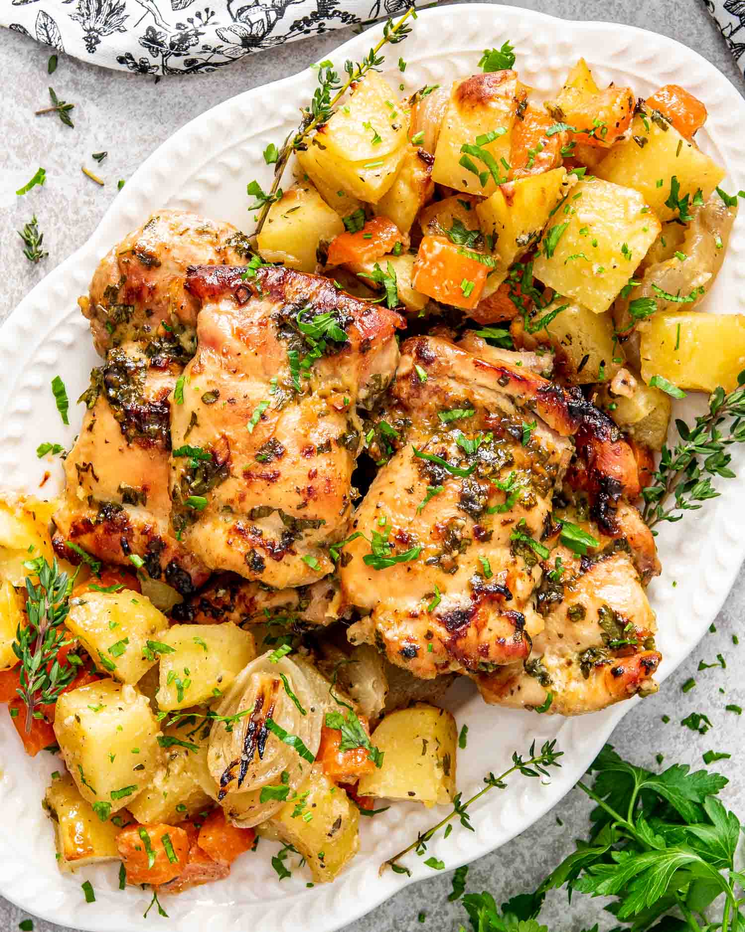baked honey mustard chicken with potatoes on a white serving platter.