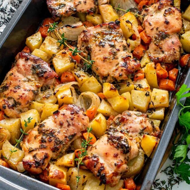 fresh out of the oven baked honey mustard chicken with potatoes in a baking pan.