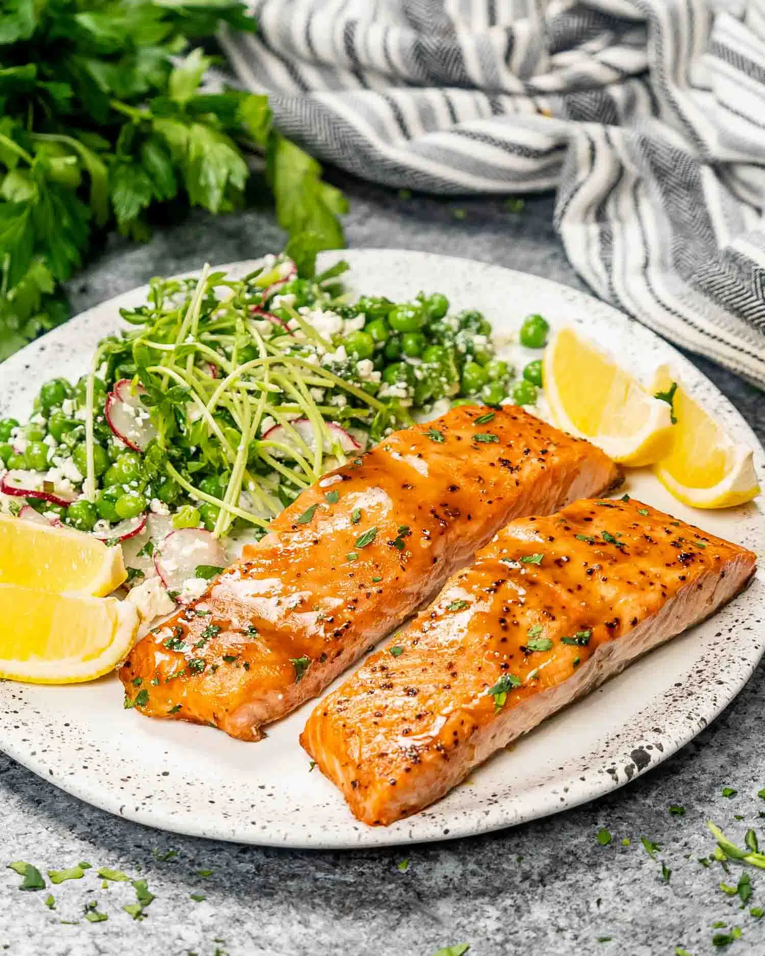 baked salmon with mustard glaze on a white plate with pea salad.