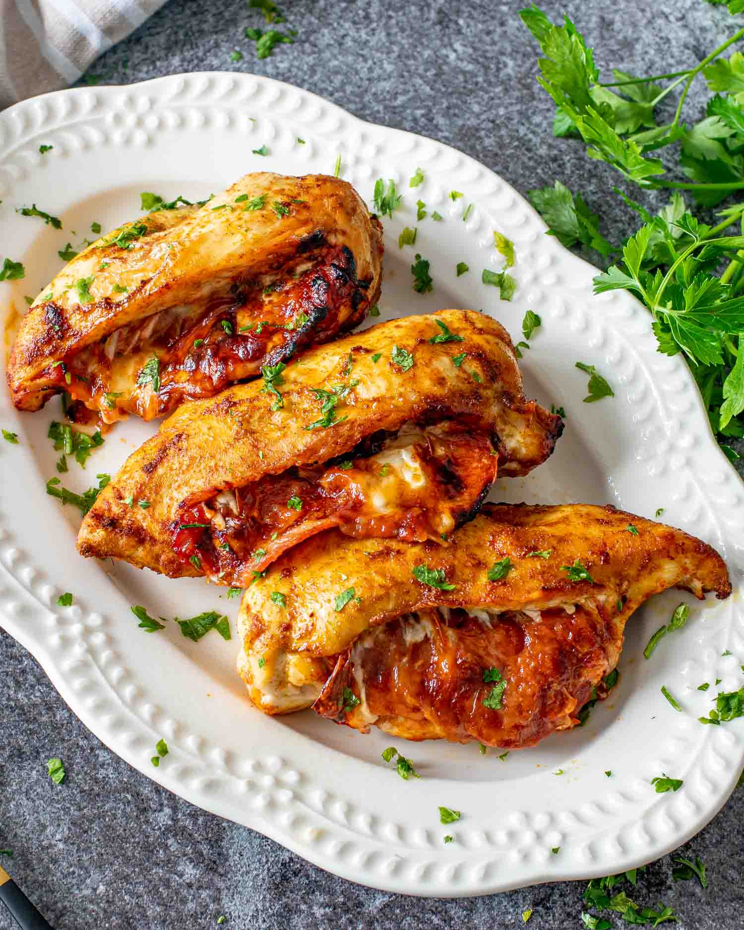 pizza stuffed chicken breasts on a white serving platter.