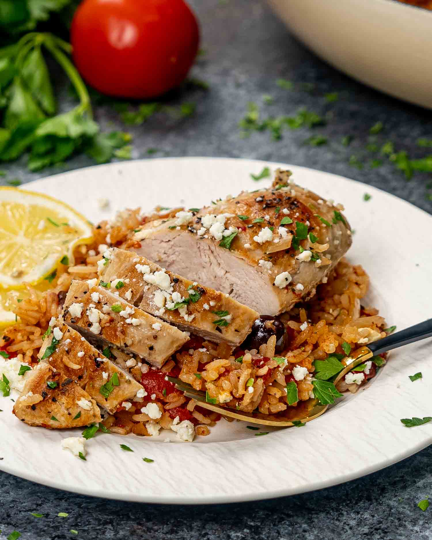 mediterranean chicken and rice on a white plate garnished with feta cheese and lemon slices.
