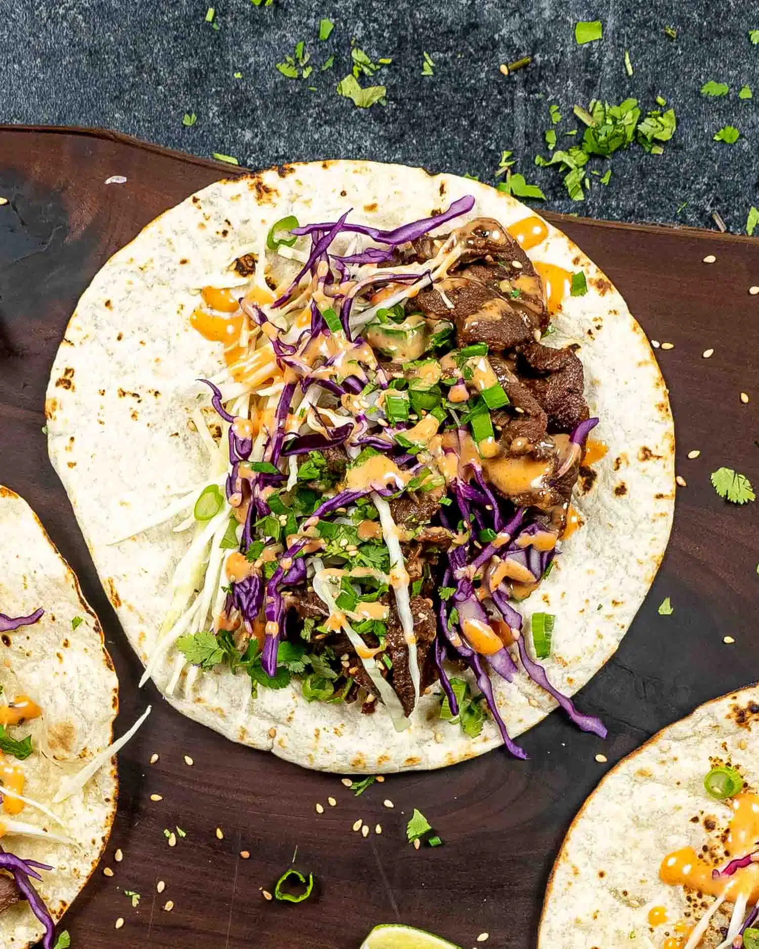 korean beef tacos on a wooden cutting board.