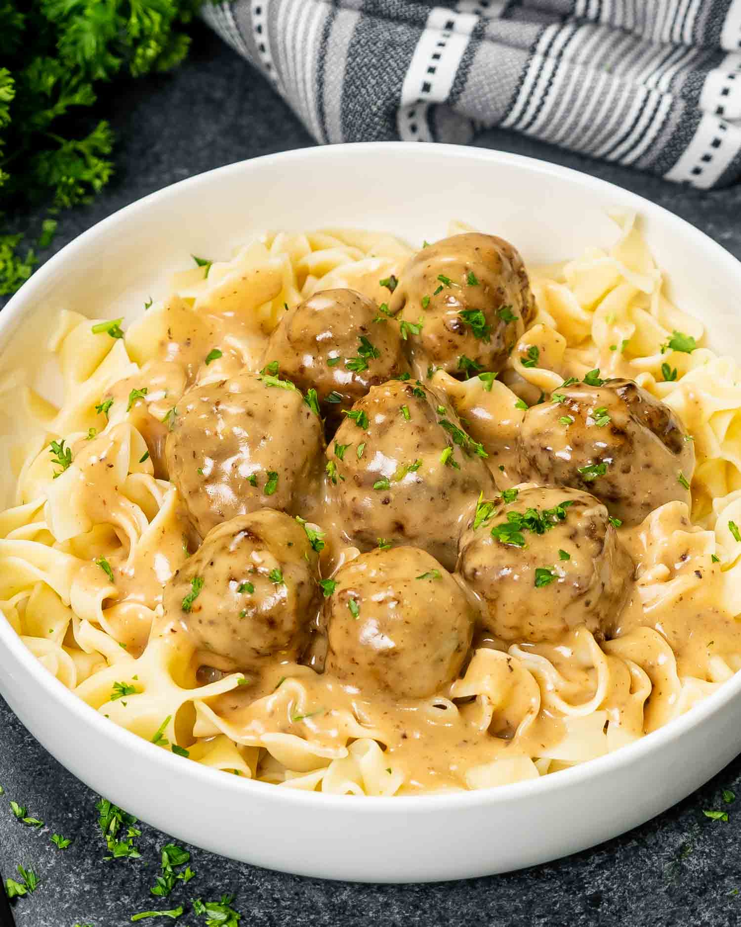 a serving of freshly made swedish meatballs over a bed of noodles.