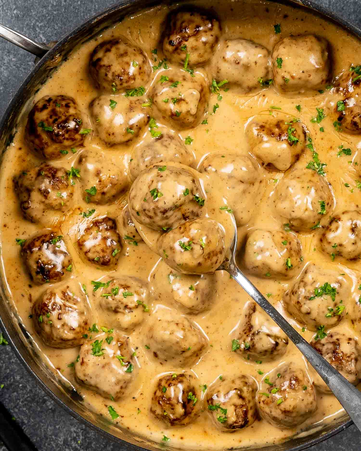swedish meatballs with lots of sauce in a skillet, freshly made and garnished with parsley.
