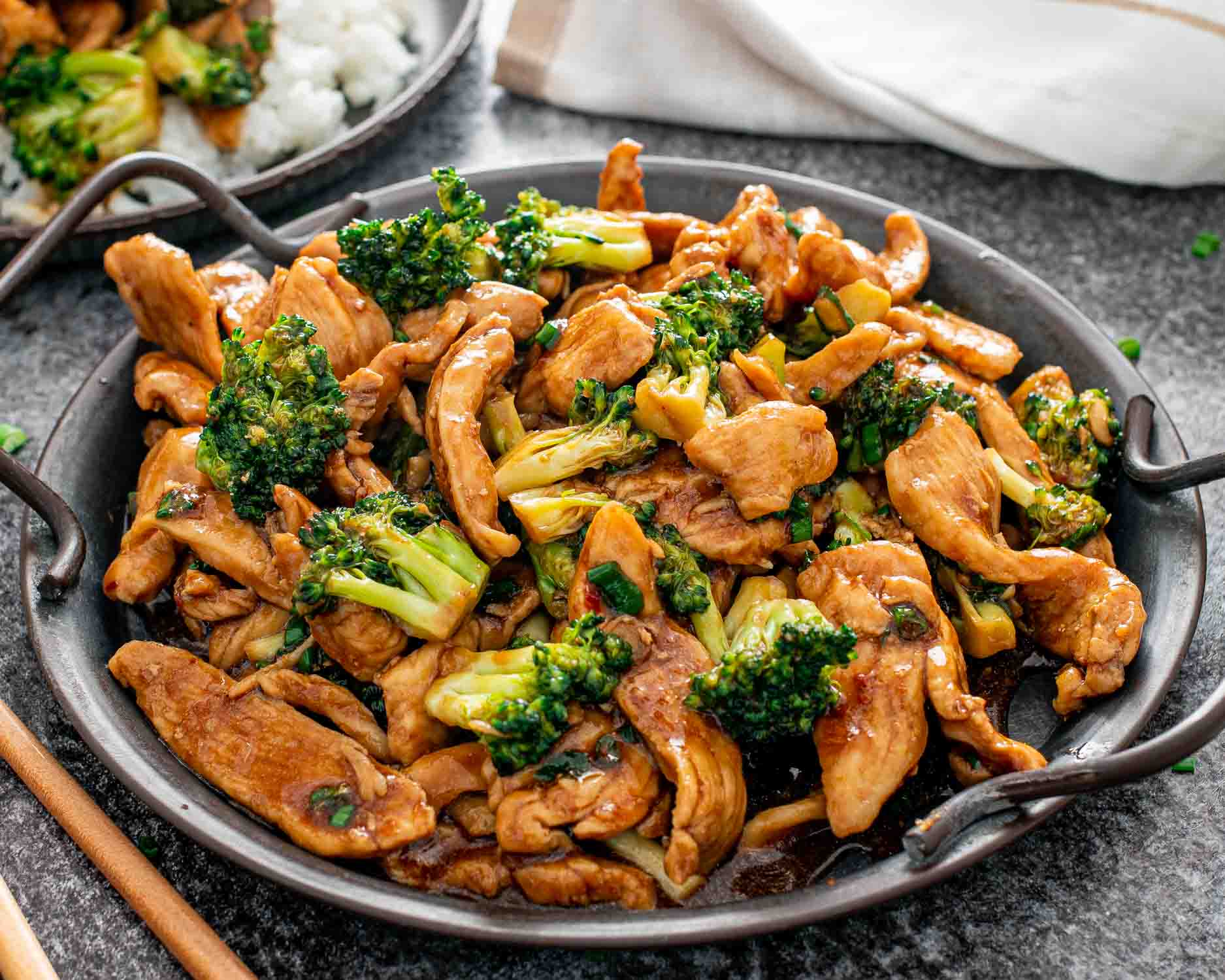 freshly made asian style chicken and broccoli on a metal plate.