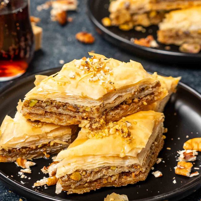 a few slices of baklava on a black plate.